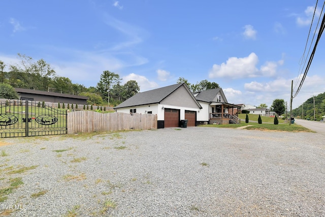 view of property exterior featuring a garage, gravel driveway, and fence