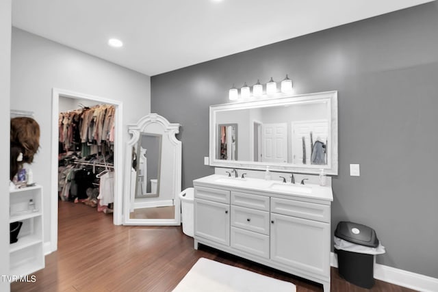 full bathroom featuring double vanity, a sink, baseboards, and wood finished floors