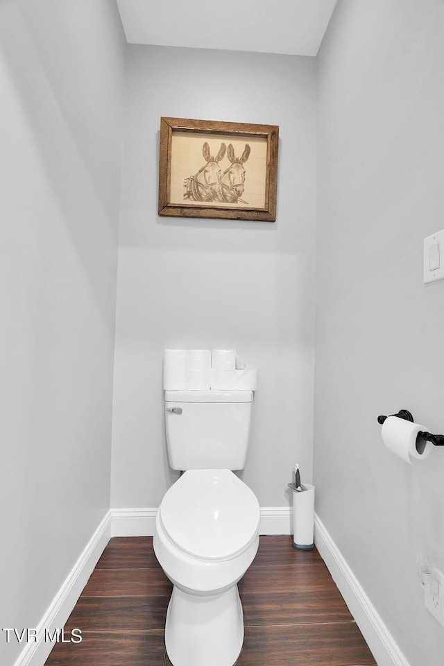 bathroom with toilet, baseboards, and wood finished floors