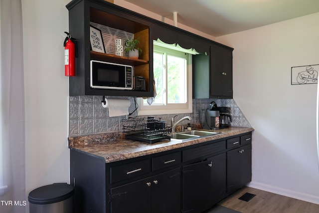 kitchen featuring sink, hardwood / wood-style floors, stainless steel microwave, and tasteful backsplash