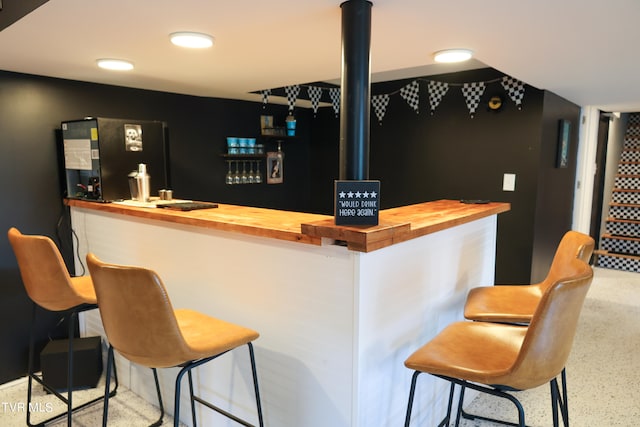 bar with butcher block counters and black fridge