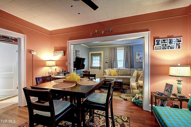 dining space featuring wood-type flooring, ornamental molding, and ceiling fan