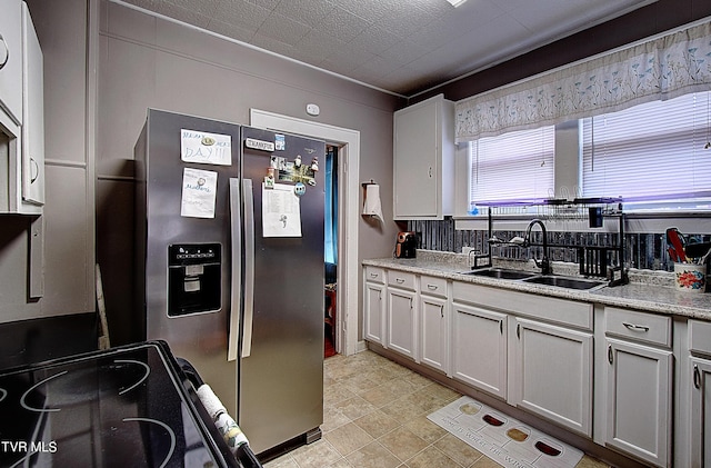 kitchen featuring white cabinetry, sink, stainless steel fridge, and electric stove