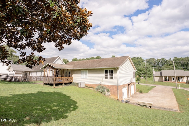 back of property featuring a garage, central air condition unit, a wooden deck, and a lawn