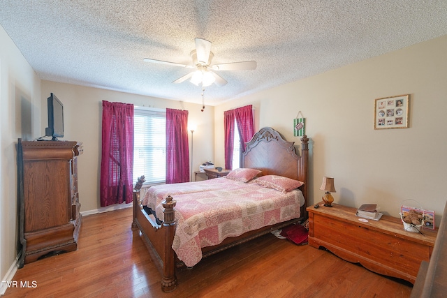 bedroom featuring ceiling fan, hardwood / wood-style flooring, and a textured ceiling