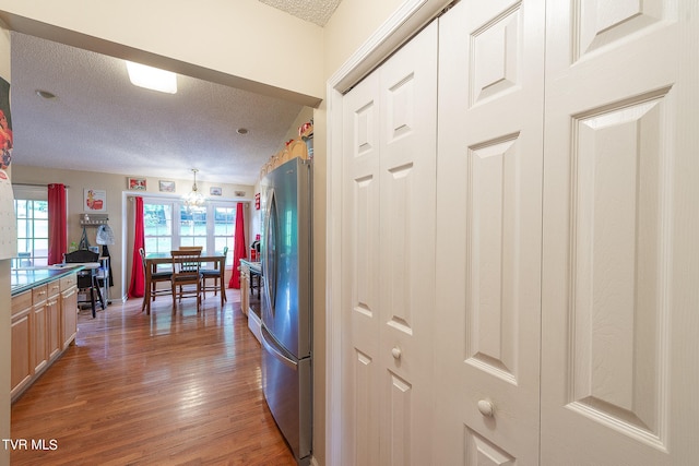 kitchen with stainless steel refrigerator, a textured ceiling, and dark wood-type flooring