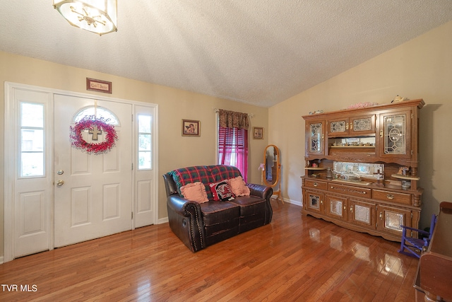 entrance foyer with a textured ceiling, plenty of natural light, lofted ceiling, and hardwood / wood-style floors