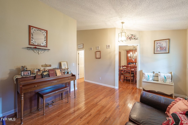 interior space featuring a textured ceiling, lofted ceiling, an inviting chandelier, and hardwood / wood-style flooring