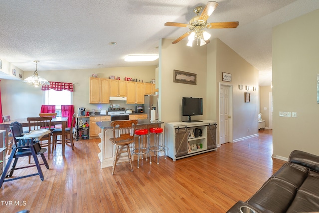 kitchen with light wood-type flooring, white electric range oven, ceiling fan with notable chandelier, a kitchen breakfast bar, and light brown cabinetry