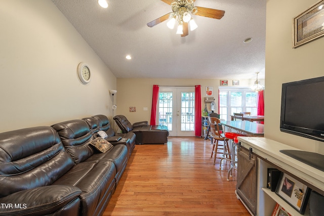 living room with light wood-type flooring, french doors, ceiling fan, and a textured ceiling