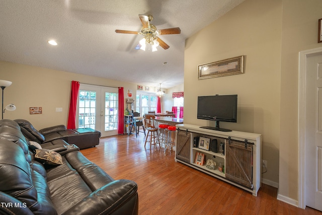 living room with hardwood / wood-style floors, vaulted ceiling, french doors, and ceiling fan