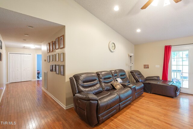 living room featuring ceiling fan, a textured ceiling, light hardwood / wood-style flooring, and lofted ceiling