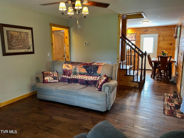 living room featuring dark hardwood / wood-style flooring, wood walls, and ceiling fan