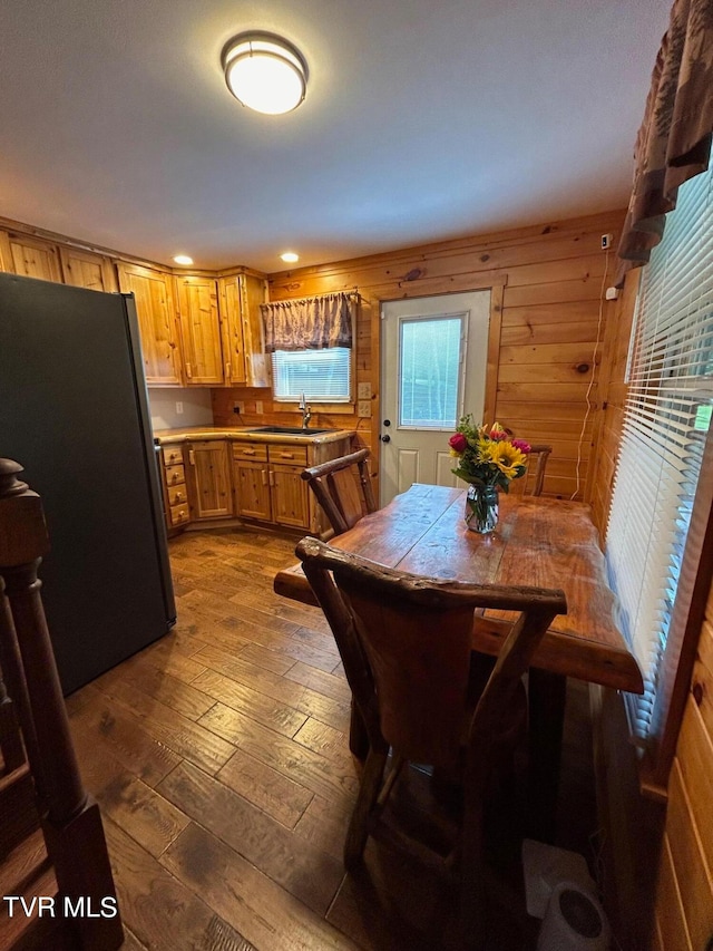 dining space featuring sink, wooden walls, and hardwood / wood-style flooring