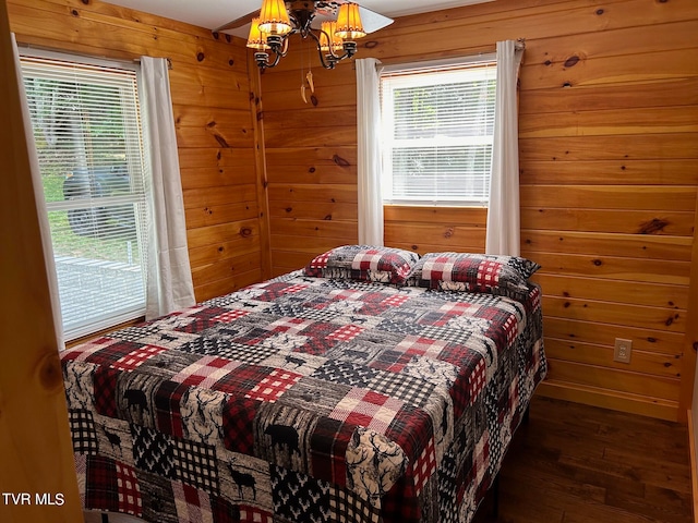 bedroom featuring wood-type flooring, a notable chandelier, and wooden walls