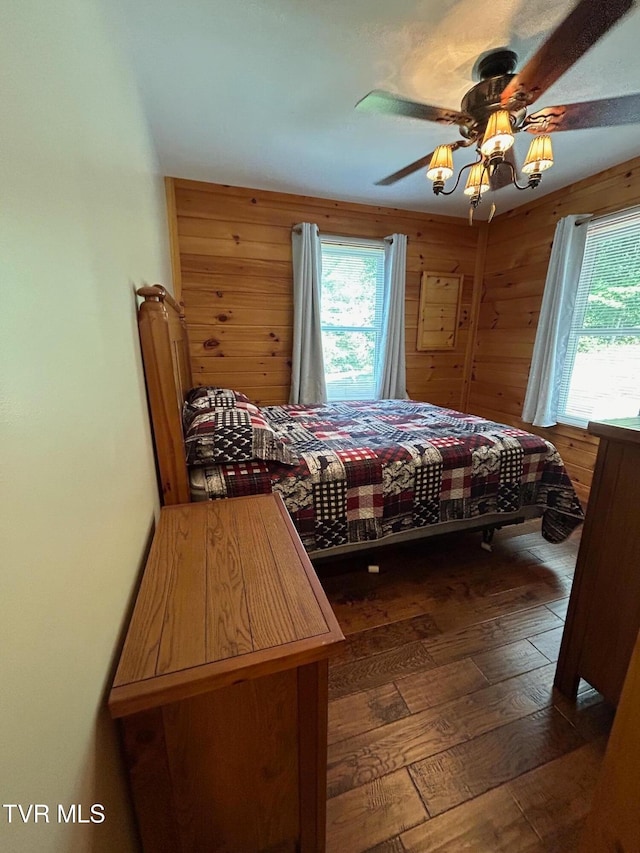 bedroom featuring ceiling fan, hardwood / wood-style floors, and wooden walls