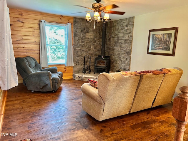 living room featuring hardwood / wood-style flooring, ceiling fan, wooden walls, and a wood stove