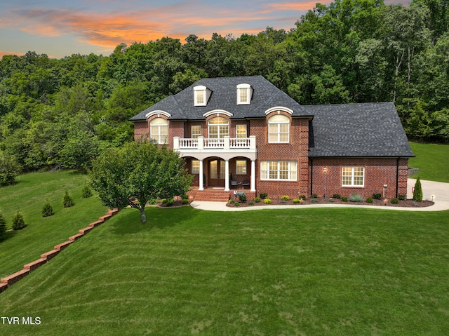 french country inspired facade featuring a balcony, a yard, and covered porch