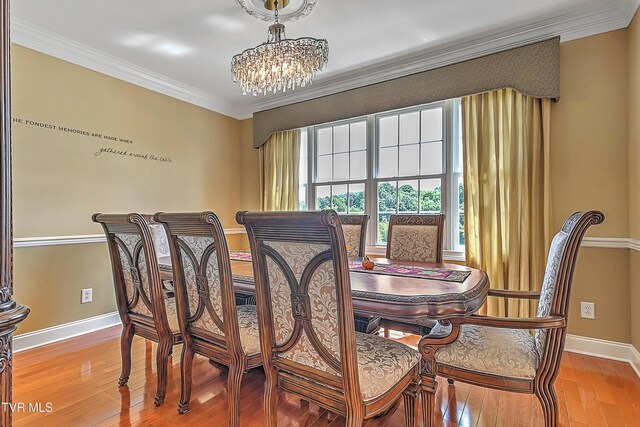 dining room with wood-type flooring, ornamental molding, and a chandelier