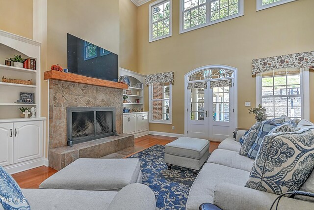 living room featuring a tile fireplace, wood-type flooring, a wealth of natural light, and built in features