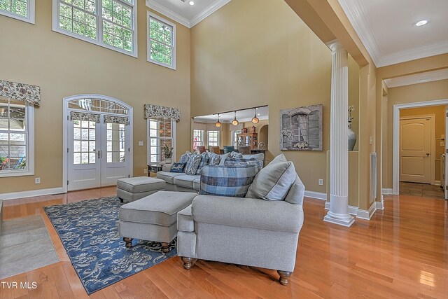 living room with french doors, ornamental molding, wood-type flooring, and ornate columns