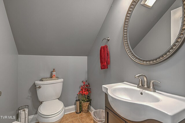 bathroom featuring vanity, tile patterned flooring, vaulted ceiling, and toilet