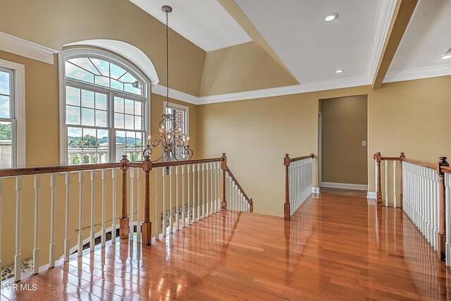 corridor with hardwood / wood-style flooring, ornamental molding, and a notable chandelier