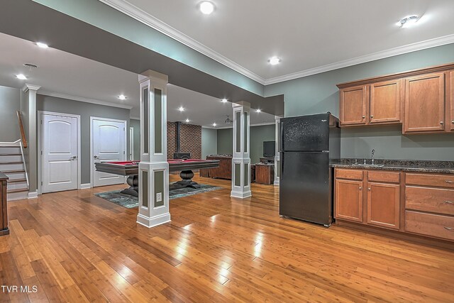 kitchen with ornate columns, black refrigerator, sink, light hardwood / wood-style floors, and crown molding