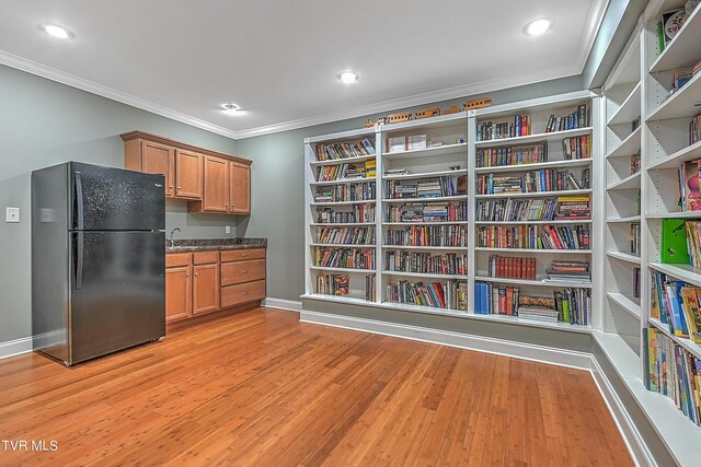 kitchen featuring black refrigerator, light hardwood / wood-style flooring, and ornamental molding