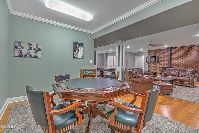 dining area with crown molding, brick wall, a wood stove, and light wood-type flooring