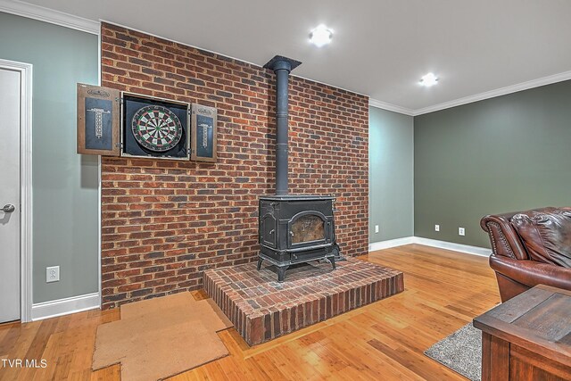 living room with crown molding, hardwood / wood-style flooring, and a wood stove