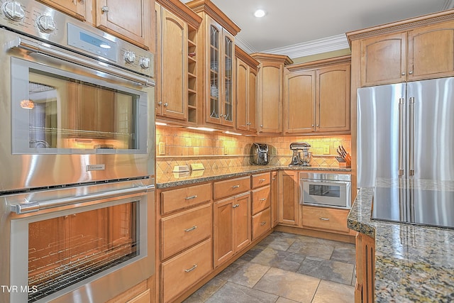 kitchen featuring stone countertops, decorative backsplash, crown molding, and appliances with stainless steel finishes