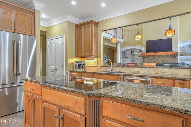 kitchen with sink, dark stone counters, ornamental molding, pendant lighting, and stainless steel appliances