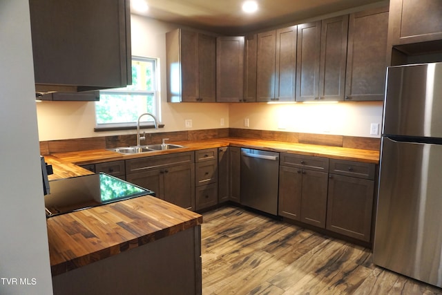 kitchen featuring hardwood / wood-style floors, appliances with stainless steel finishes, sink, and wood counters