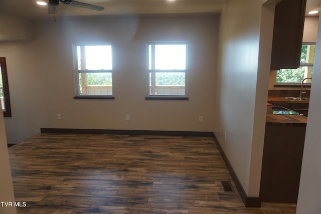 unfurnished room with a healthy amount of sunlight, sink, ceiling fan, and dark hardwood / wood-style floors