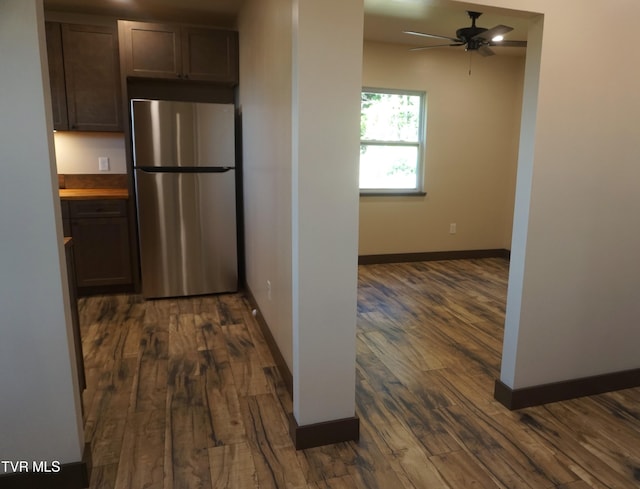 kitchen featuring stainless steel fridge, butcher block countertops, ceiling fan, dark wood-type flooring, and dark brown cabinetry