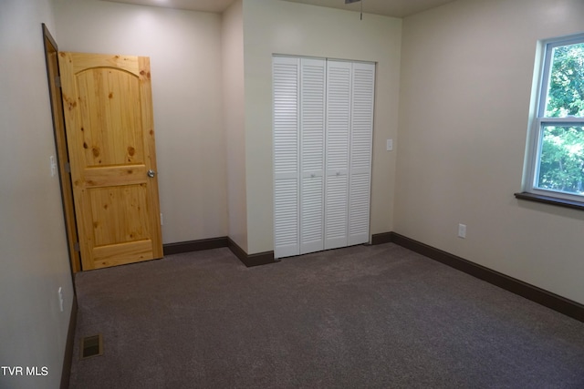 unfurnished bedroom featuring a closet and dark colored carpet