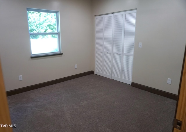 unfurnished bedroom featuring dark carpet and a closet