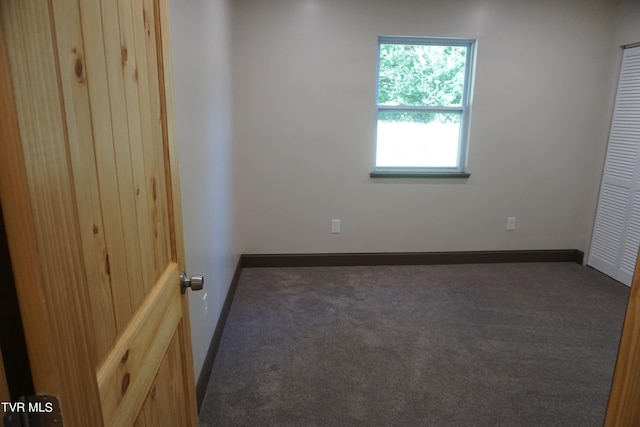 unfurnished room with dark carpet