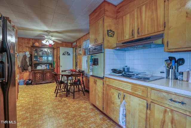 kitchen with ceiling fan, oven, black fridge, tasteful backsplash, and gas cooktop