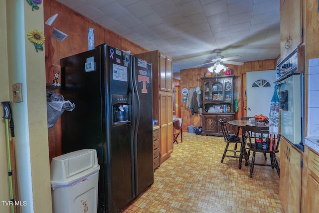 kitchen with ceiling fan, wooden walls, light tile patterned flooring, and black appliances