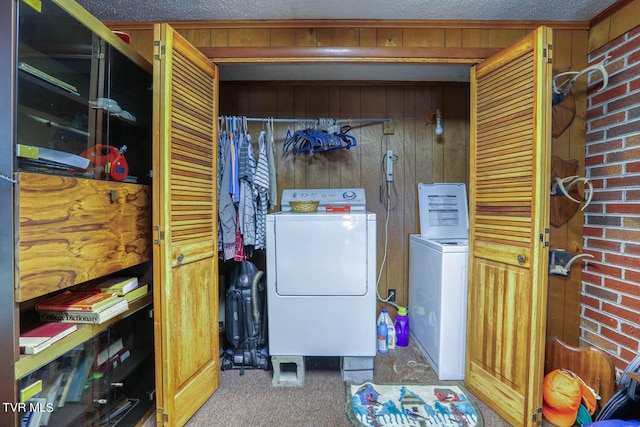 clothes washing area with wooden walls, separate washer and dryer, and carpet