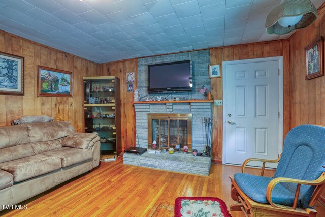 living room featuring wood walls, light hardwood / wood-style flooring, and a fireplace