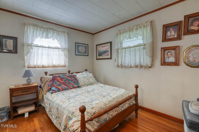 bedroom with crown molding, multiple windows, and hardwood / wood-style flooring