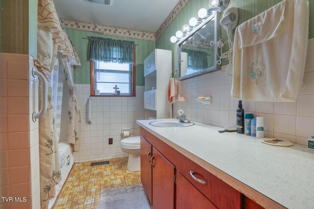 full bathroom featuring toilet, tile patterned flooring, vanity, tile walls, and shower / tub combo