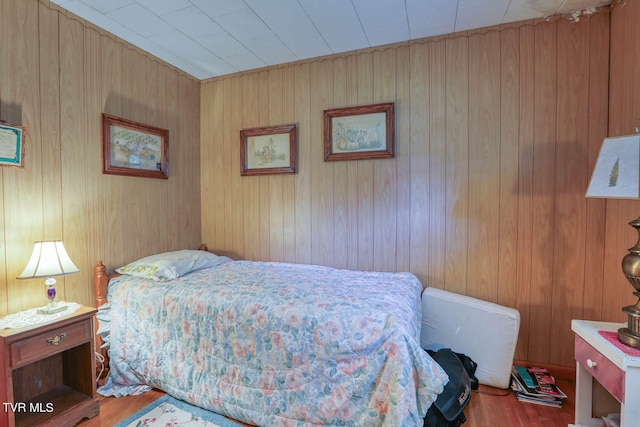 bedroom with hardwood / wood-style flooring and wooden walls