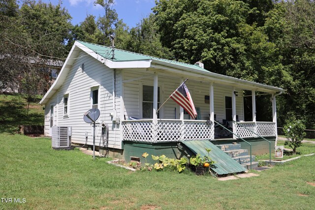 view of front facade with covered porch, central AC unit, and a front yard