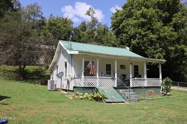 view of front facade with cooling unit, a porch, and a front yard