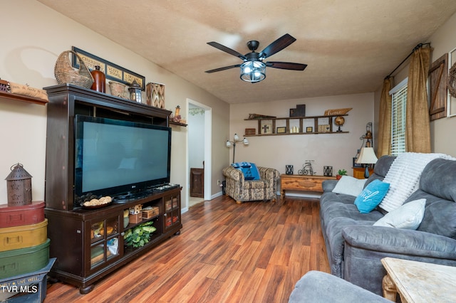 living room featuring ceiling fan, dark wood-type flooring, and a textured ceiling