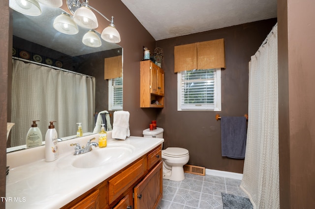 bathroom with tile patterned floors, vaulted ceiling, vanity, and toilet